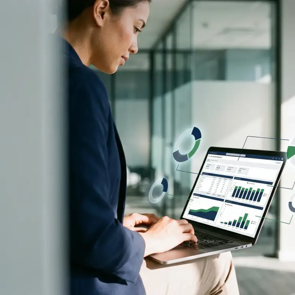 Een zakelijke professional die op een laptop een dashboard voor de toewijzing van cloudkosten analyseert in een modern kantoor met glazen wanden, met diagrammen van de afdelingssegmenten.